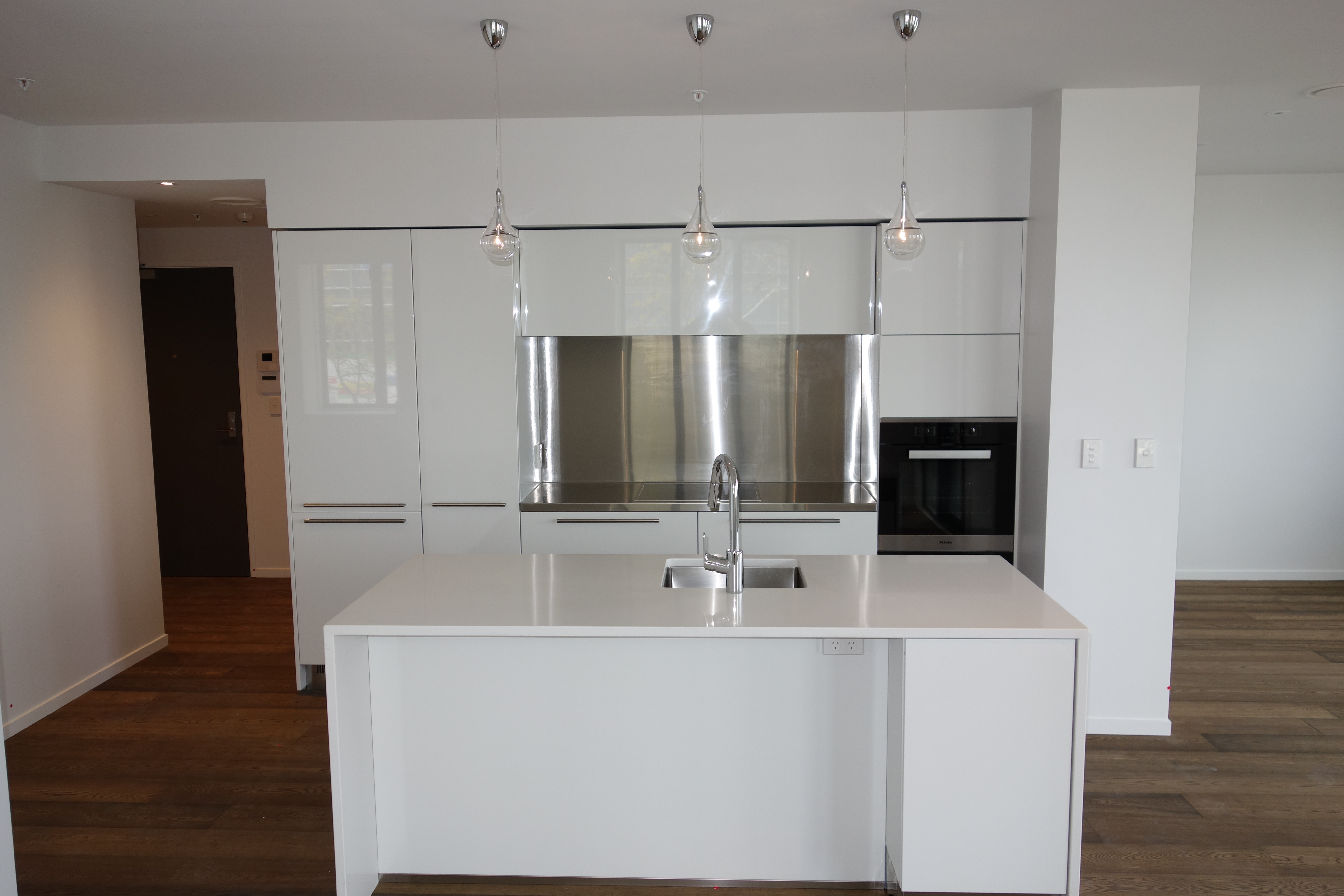 Gloss white kitchen with stainless steel splashback