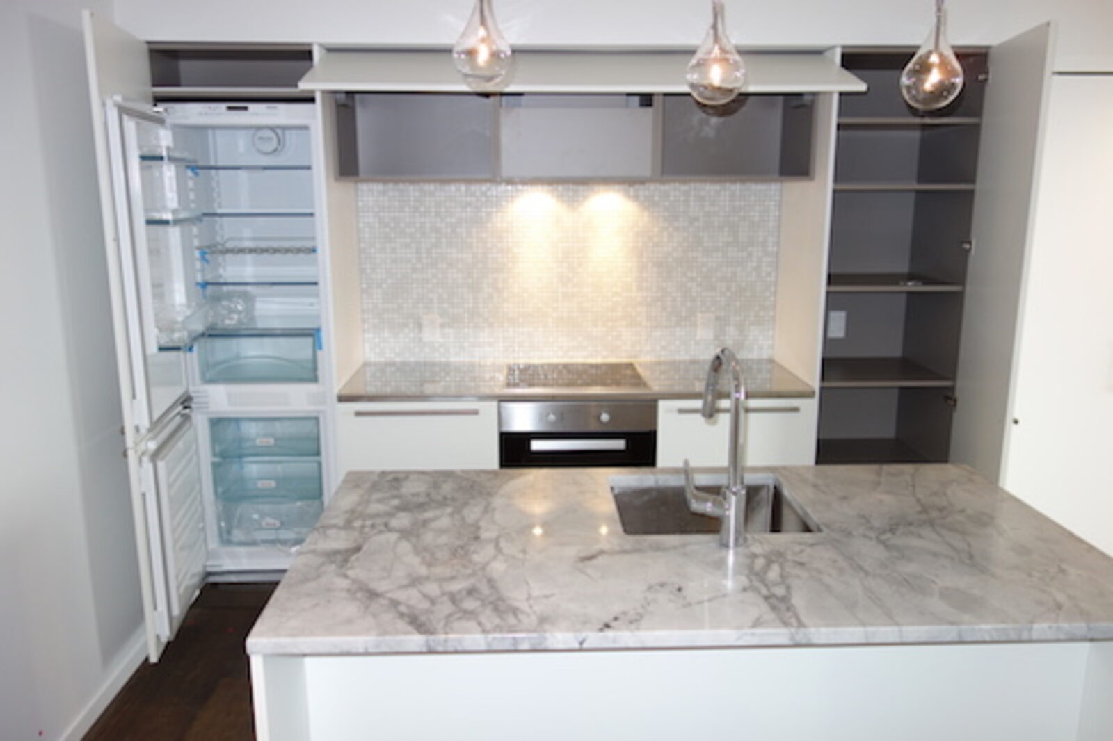 Kitchen with marble benchtop, pendant lights and integrated fridge