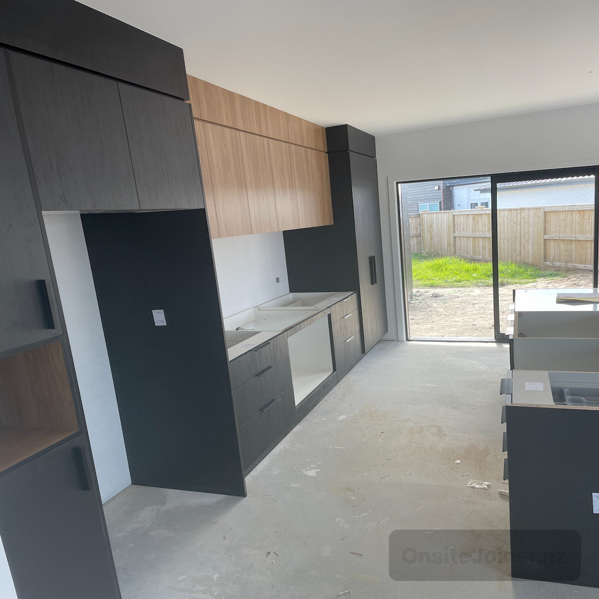 New kitchen install with dark and timber cabinetry — awaiting benchtops