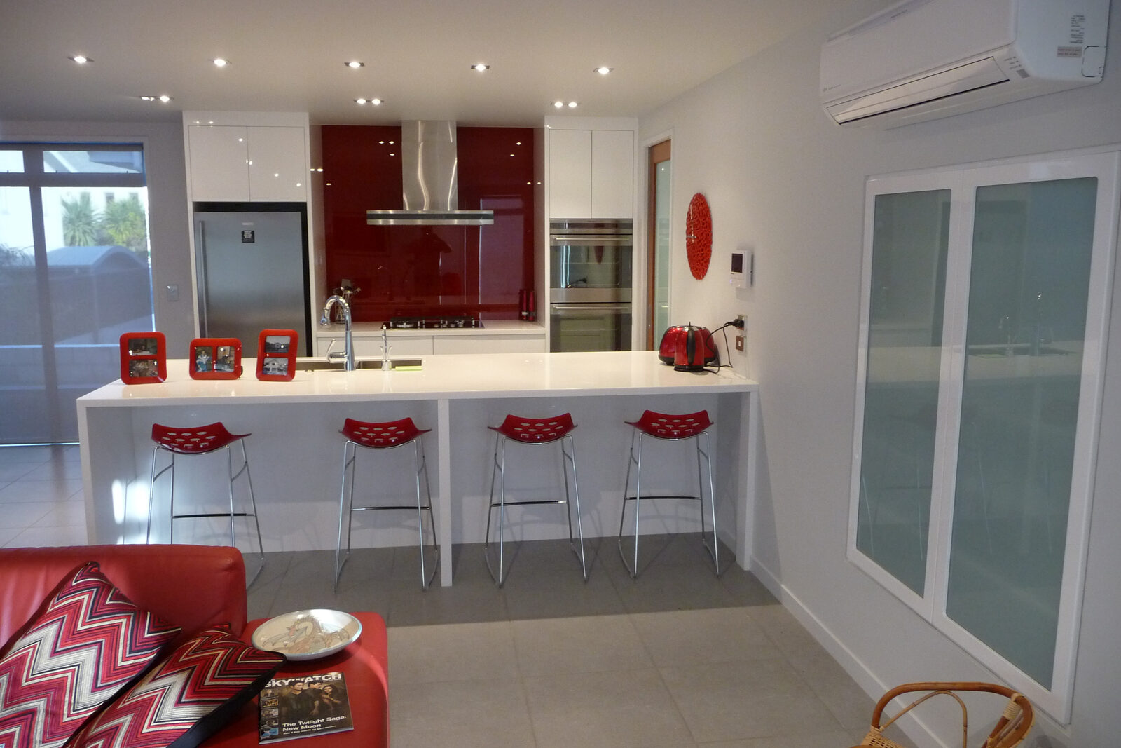 White kitchen with red glass splashback and breakfast bar