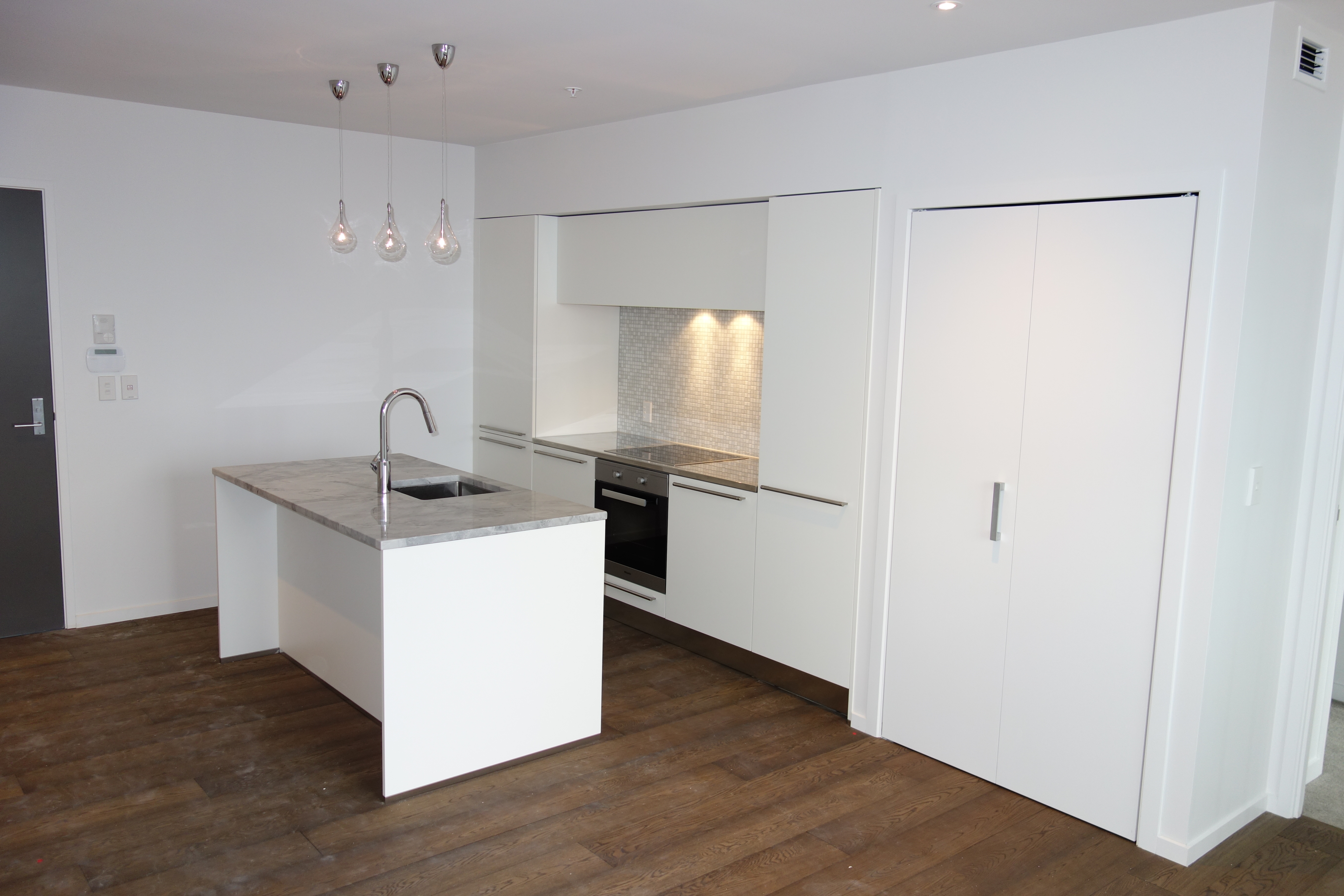 Sleek white kitchen with marble top and timber flooring